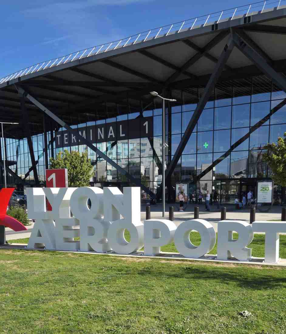 Enseigne géante Lyon Aéroport devant le Terminal 1 pour service de taxi Lyon Aéroport.